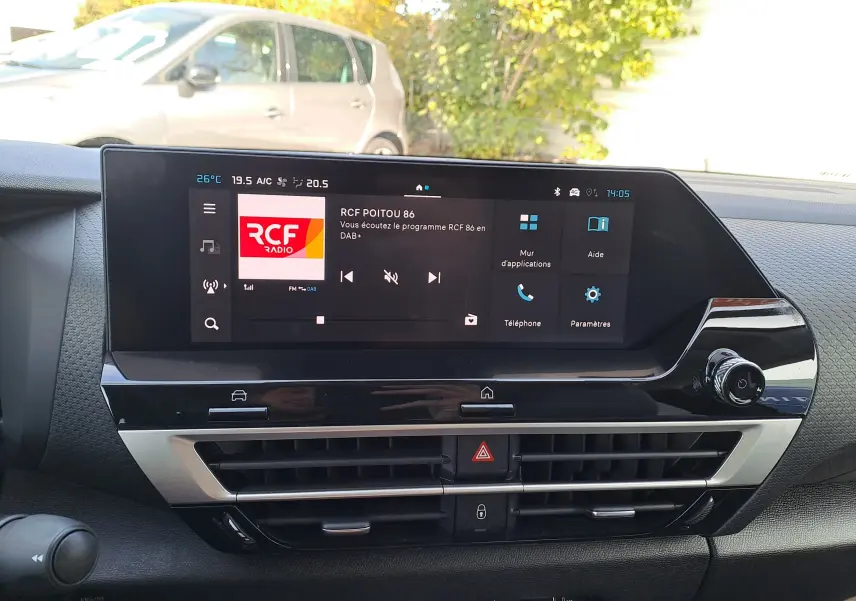 Écran tactile central de la Citroën C4 hybride 2025 affichant la radio RCF, avec tableau de bord noir moderne.