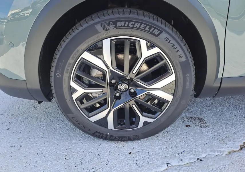 Gros plan sur la roue avant gauche d'une Citroën C4 hybride Manhattan Green avec jante alliage bicolore et pneu Michelin.