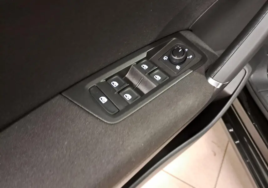 Gros plan sur les commandes des vitres et rétroviseurs côté conducteur du Volkswagen Touran 2025 en noir Grenadille.