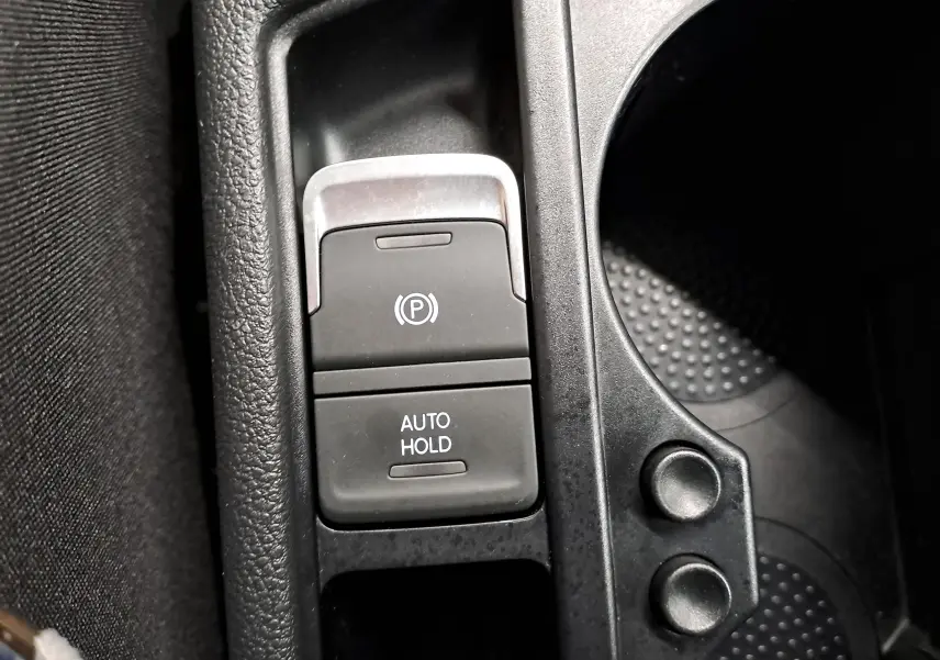 Gros plan sur la console centrale du Volkswagen Touran 2025, montrant les boutons de frein de parking électronique et Auto Hold.
