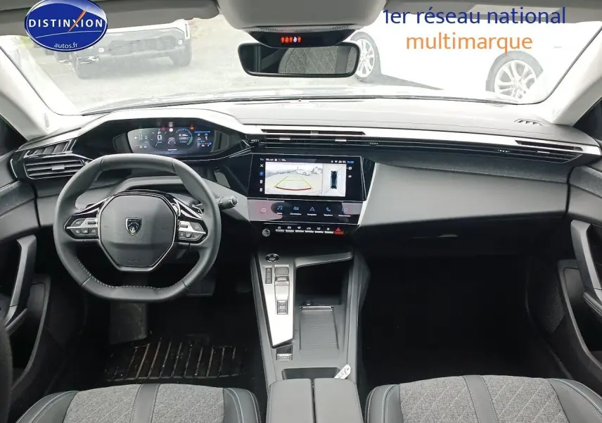 Vue intérieure avant du Peugeot 408 Hybrid 145 allure 2024, tableau de bord moderne avec écran tactile et volant multifonction cuir.