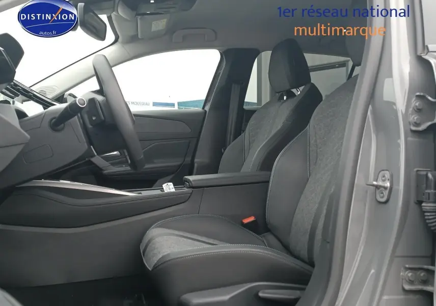 Vue intérieure côté conducteur de la Peugeot 408 Hybrid 145 allure gris sellenium, sièges bi-matière et accoudoir central visible.