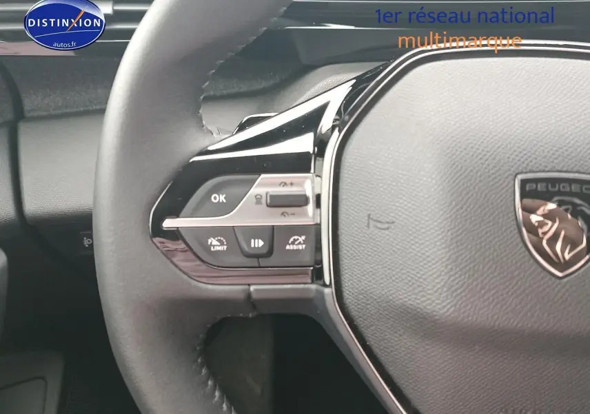 Gros plan sur le volant cuir multifonction de la Peugeot 408 Hybrid 145 allure gris sélénite, avec commandes intégrées.