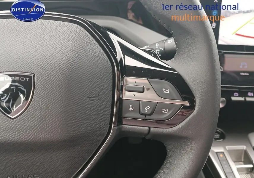 Gros plan sur le volant cuir multifonction de la Peugeot 408 gris sellenium avec commandes audio et vocales visibles.
