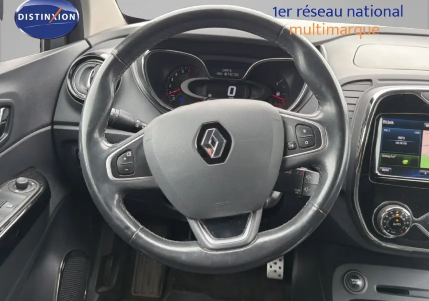 Vue rapprochée du volant en cuir noir avec logo Renault et tableau de bord numérique du Captur gris Cassiopée.