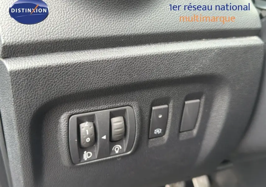 Gros plan sur les commandes d'éclairage et d'assistance du tableau de bord d'un Renault Captur gris Cassiopée.