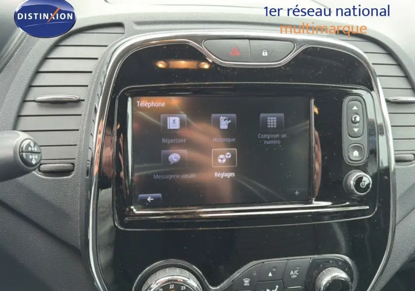 Tableau de bord de Renault Captur 2016 avec écran tactile et commandes de climatisation en vue frontale rapprochée.