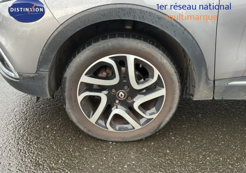 Gros plan sur la roue avant gauche d’un Renault Captur gris Cassiopée avec jante alliage bicolore et logo Renault central.