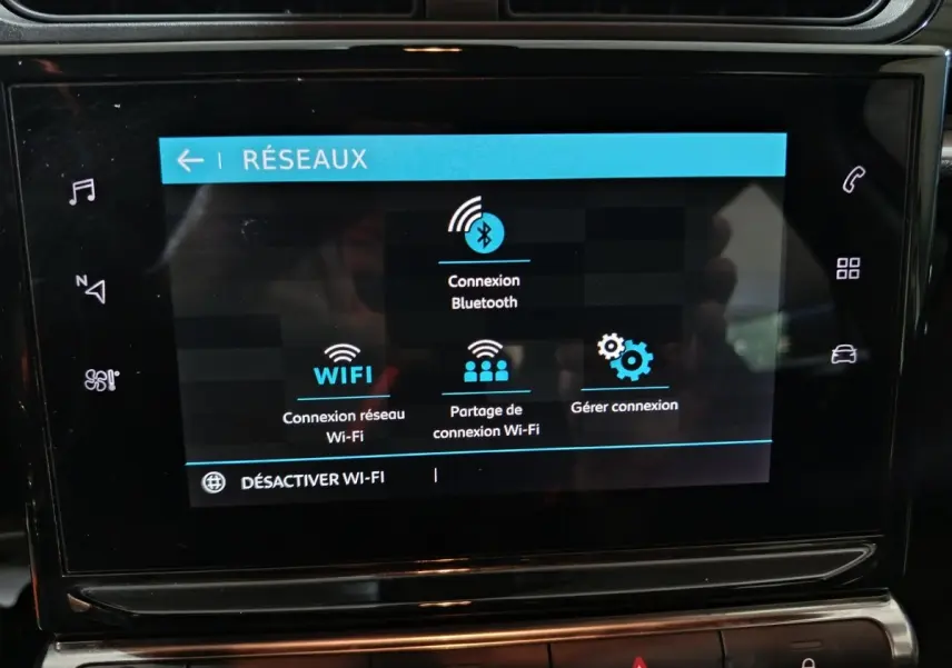 Écran tactile central du tableau de bord de la Citroën C3 2024 gris foncé affichant les options de connexion réseau Bluetooth et Wi-Fi.