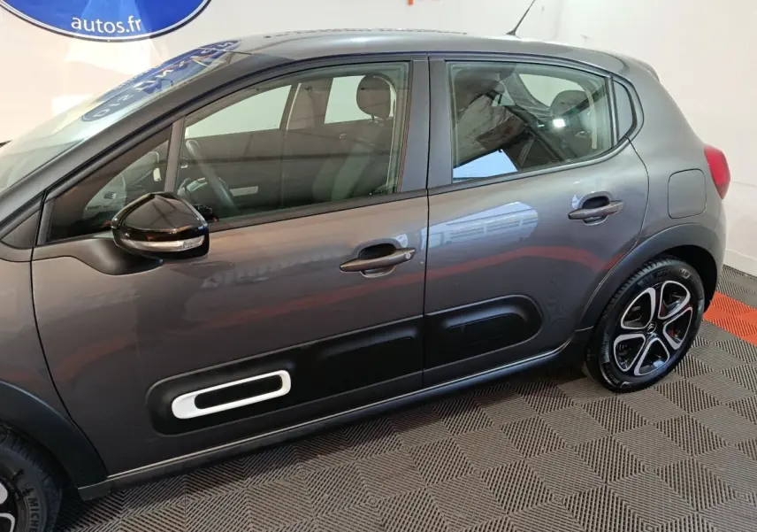 Vue de profil côté gauche de la Citroën C3 2024 gris foncé avec protection latérale noire et jantes stylisées.