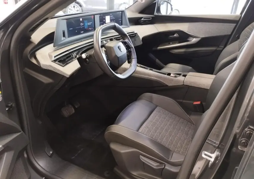 Intérieur avant droit du Peugeot 5008 gris titanium 2025, volant compact, tableau de bord numérique et sellerie tissu cuir.