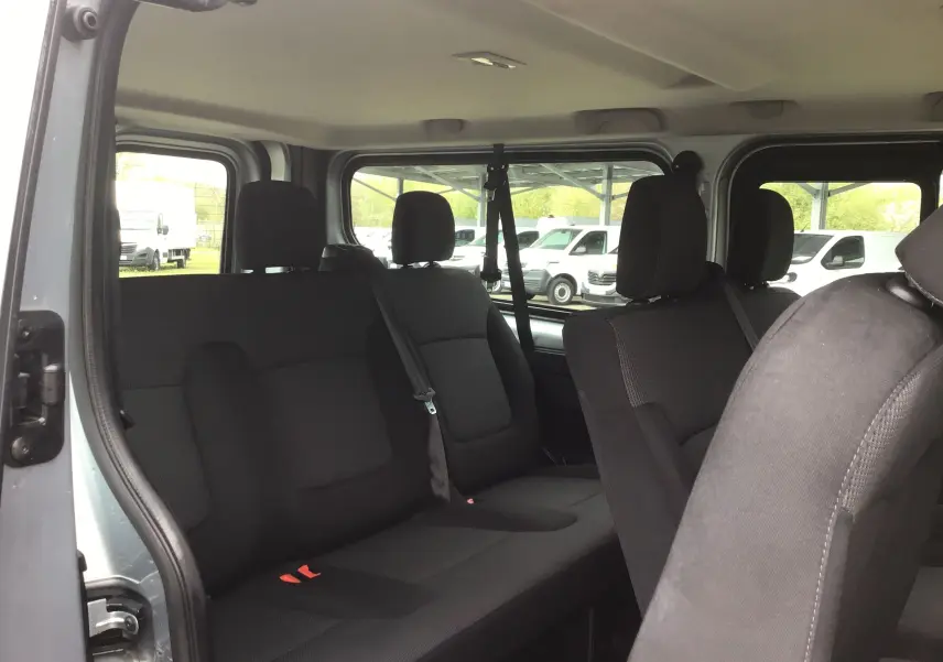 Vue intérieure côté gauche du Renault Trafic Combi gris clair, montrant les sièges noirs et ceintures de sécurité.