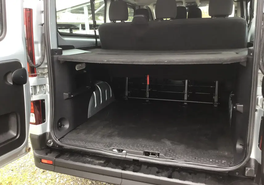 Vue arrière ouverte du Renault Trafic Combi gris clair métal, montrant le coffre spacieux et la banquette arrière.