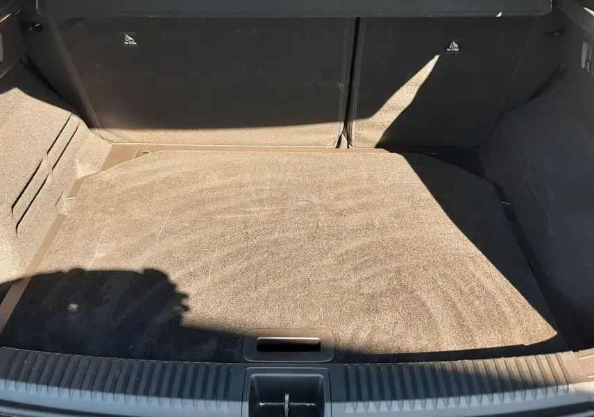 Coffre ouvert vu de l'arrière d'un Renault Austral gris schiste avec intérieur noir, montrant un espace de chargement vide.