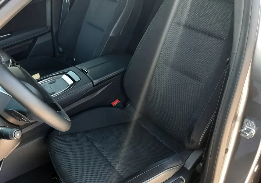 Vue intérieure côté conducteur du Renault Austral 2025, sièges noirs en tissu et cuir avec surpiqûres blanches.