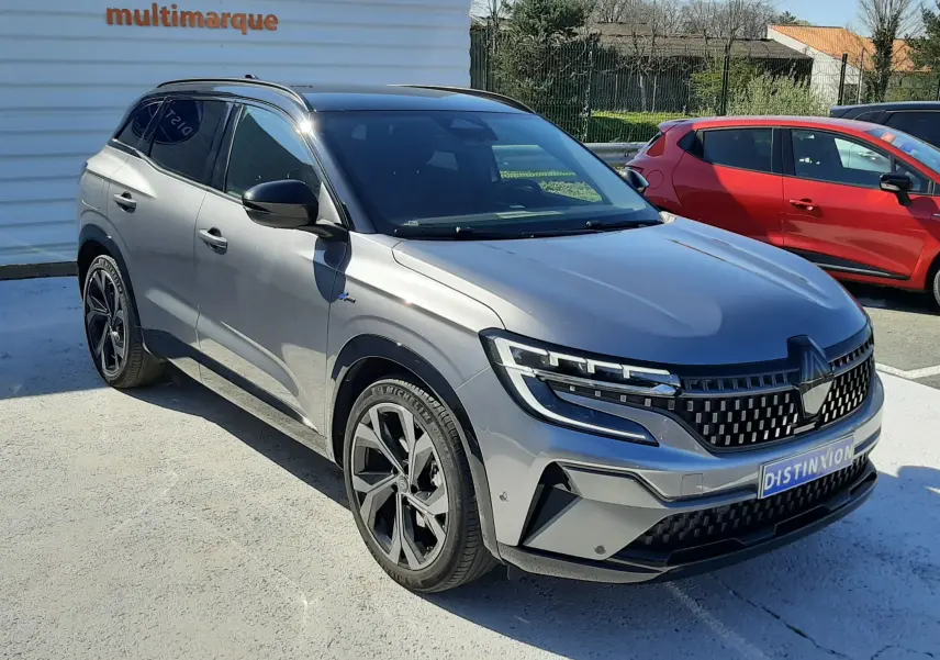 Vue 3/4 avant d'un Renault Austral gris schiste avec toit noir, mettant en valeur ses optiques LED et sa calandre distinctive.