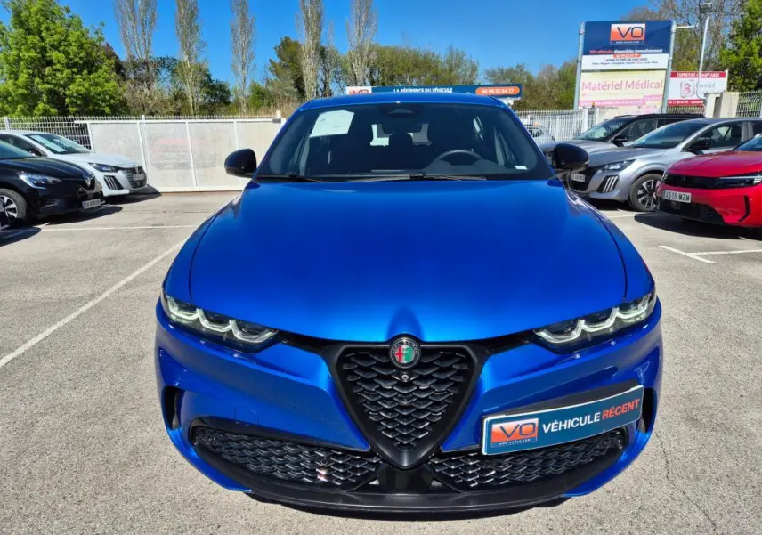 Vue avant d'une Alfa Romeo Tonale bleu vif, mettant en valeur sa calandre triangulaire et ses phares LED distinctifs.