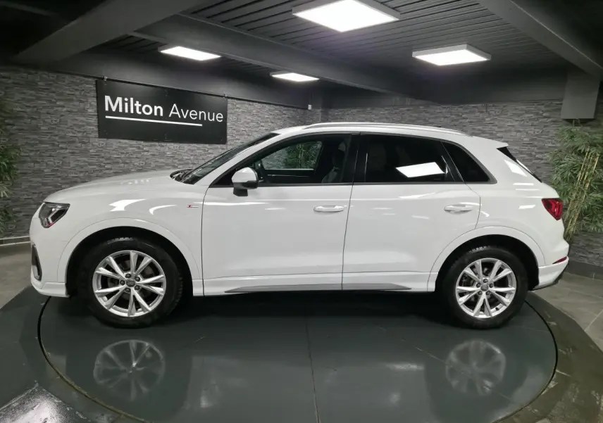 Audi Q3 blanc en vue de profil côté gauche, avec jantes alliage 5 branches doubles et vitres teintées.