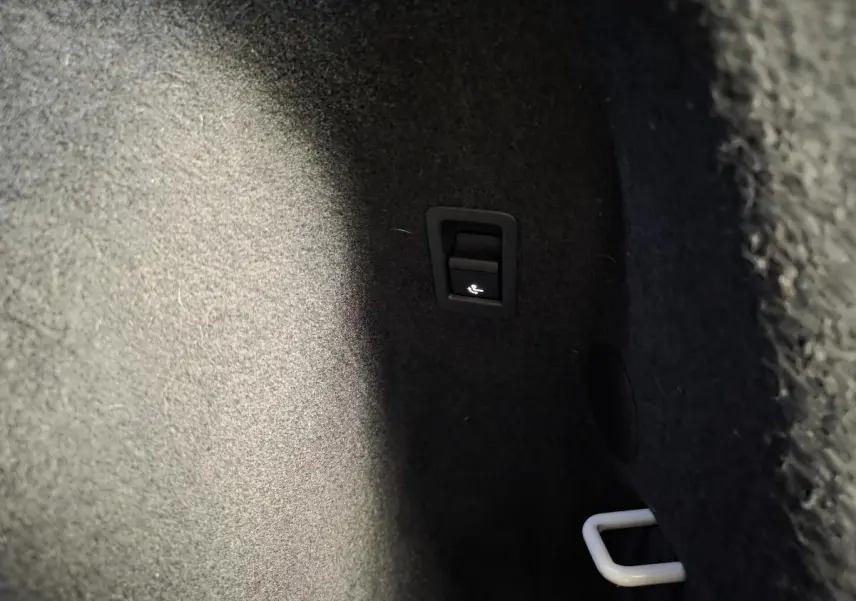Détail du coffre d’Audi Q3 blanc 2019 montrant le levier d’ouverture de la trappe à skis.