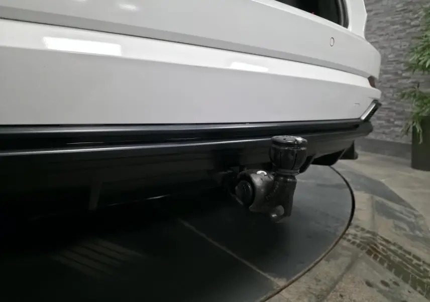 Gros plan sur le crochet d'attelage amovible à l'arrière d'un Audi Q3 blanc, finition S-Line, vue centrée.