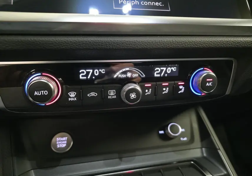 Détail de la console centrale de l’Audi Q3 blanc 2019, affichage de la climatisation à 27°C avec commandes tactiles et bouton start/stop.