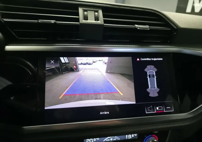 Écran central de l'Audi Q3 2019 blanc montrant la caméra de recul avec lignes de guidage et alertes de trajectoire.