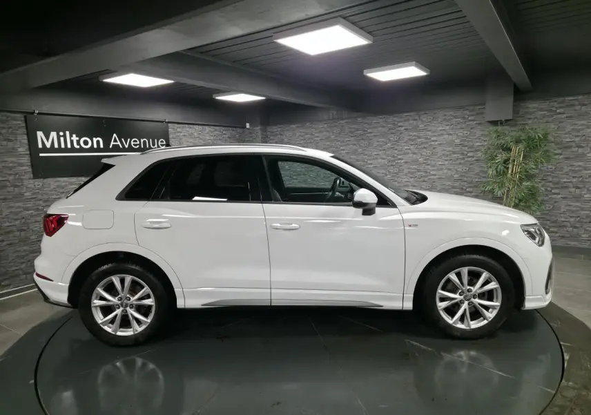 Vue latérale droite d'un Audi Q3 blanc 2019 S-Line avec jantes alliage 5 branches doubles dans un showroom.