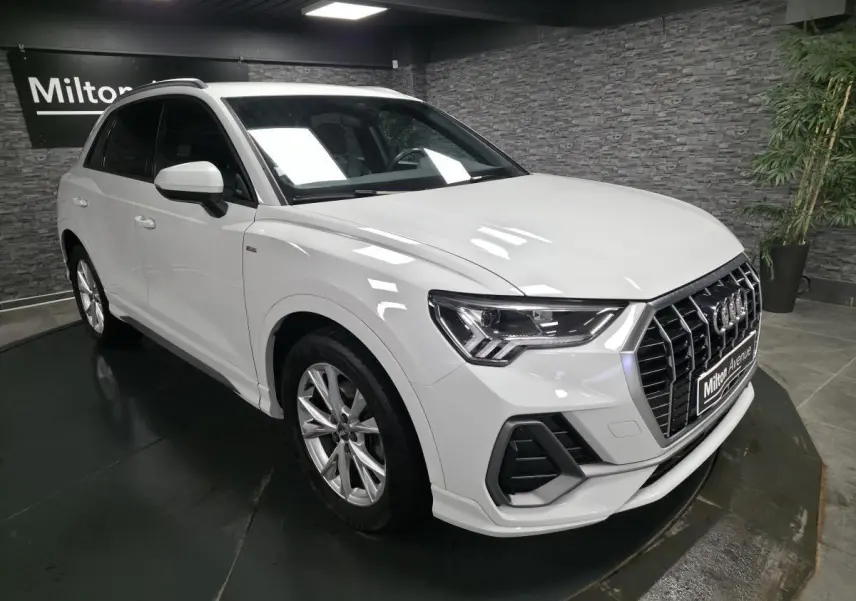 Audi Q3 blanc en vue 3/4 avant droit, avec calandre Singleframe noire et jantes alliage 5 branches doubles.