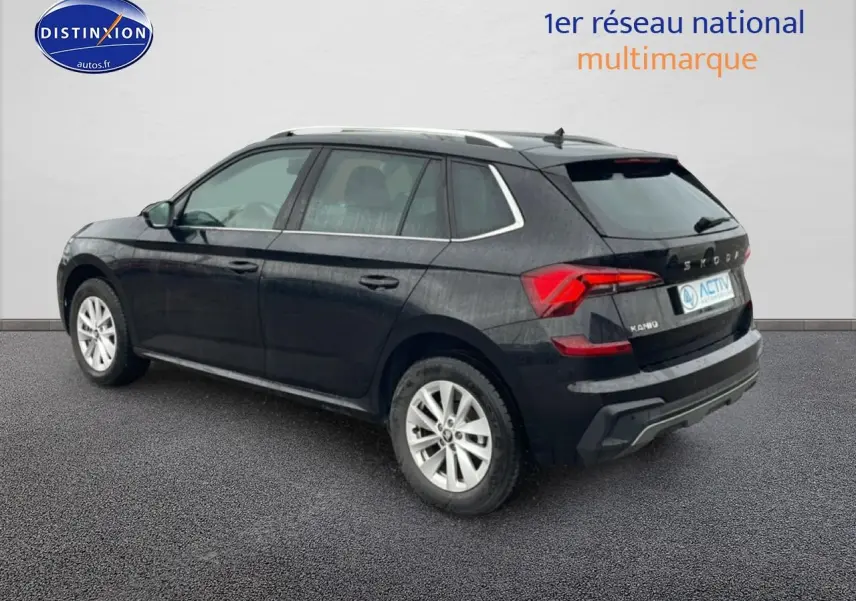 Vue 3/4 arrière droite d’un Skoda Kamiq noir 2025 avec jantes alu et barres de toit chromées.