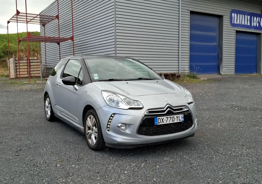 Citroën DS3 gris clair vue 3/4 avant droit, avec jantes alliage et feux diurnes à LED visibles.