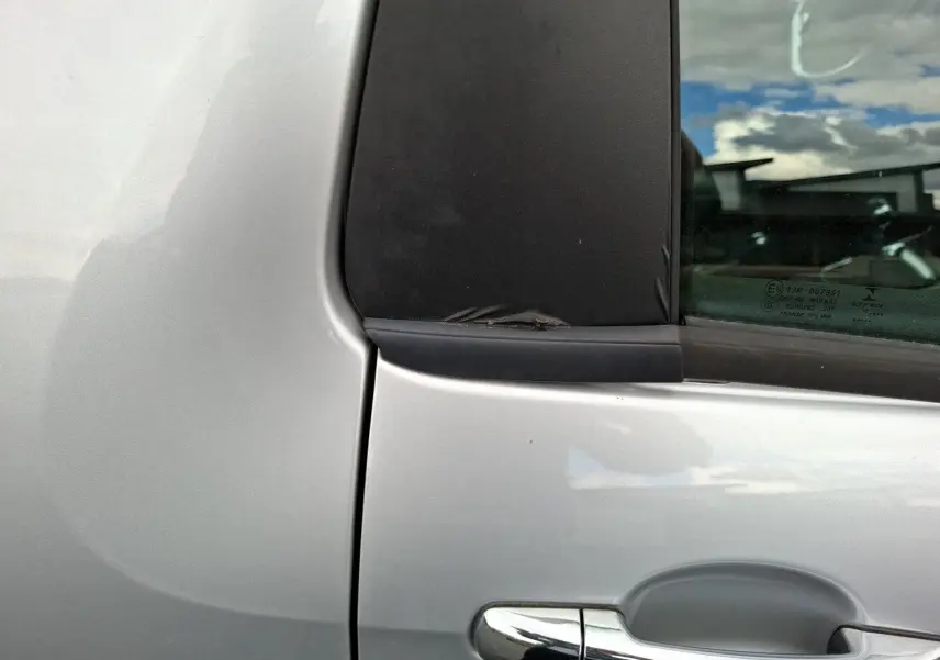 Détail de la poignée de porte côté gauche d'une Citroën DS3 gris clair avec fenêtre arrière surteintée.