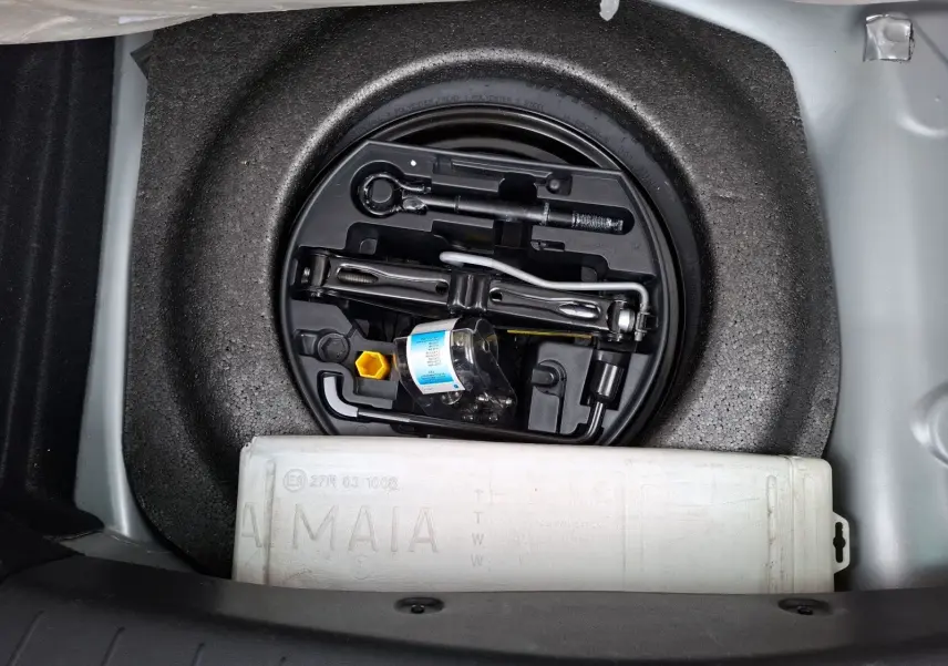Vue plongeante sur le coffre ouvert d'une Citroën DS3 gris clair, montrant la roue de secours et les outils de bord.