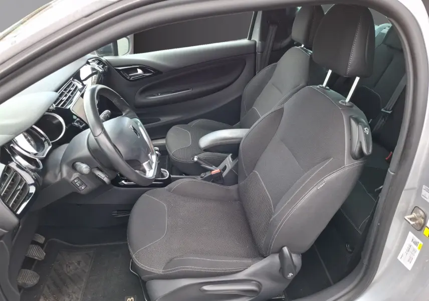 Vue intérieure côté conducteur d'une Citroën DS3 gris clair de 2015, sièges tissu noirs et tableau de bord moderne.