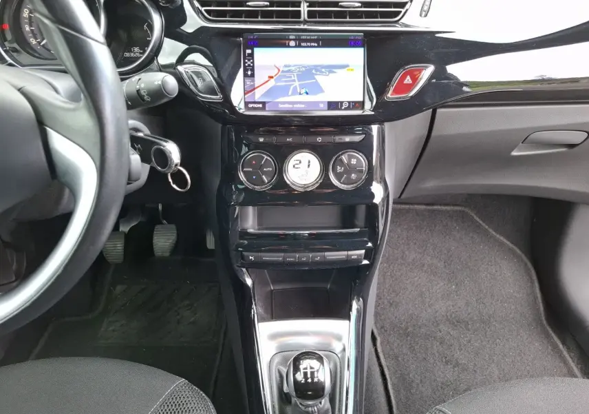 Vue intérieure centrée sur la console centrale d'une Citroën DS3 1.2 PureTech 110 so chic avec écran GPS et levier de vitesse manuel.