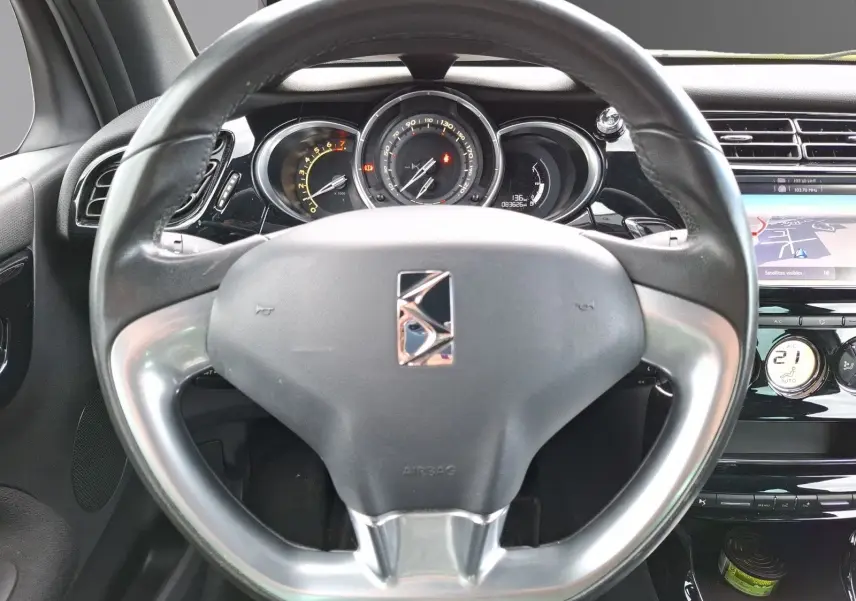 Vue rapprochée du volant et du tableau de bord d'une Citroën DS3 gris clair avec écran GPS et commandes intégrées.