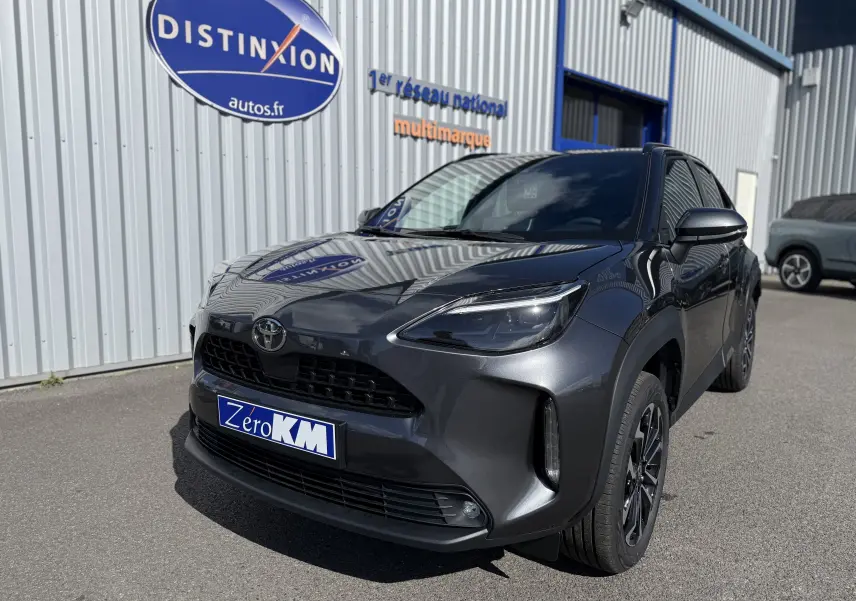 Toyota Yaris Cross 1.5 Hybrid gris atlas métal vue 3/4 avant avec calandre noire et jantes foncées.