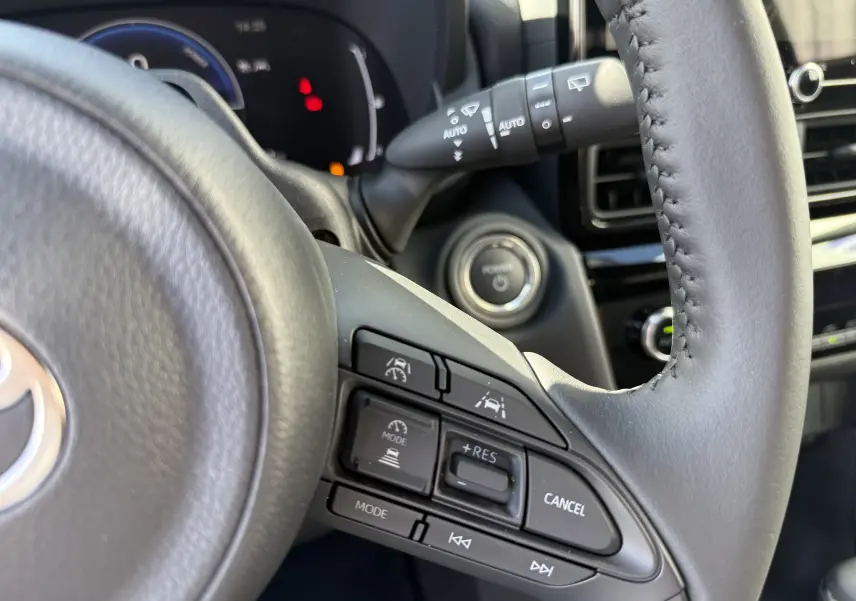 Gros plan sur le volant gris foncé du Toyota Yaris Cross 2026, montrant les commandes de régulateur et d’aide à la conduite.