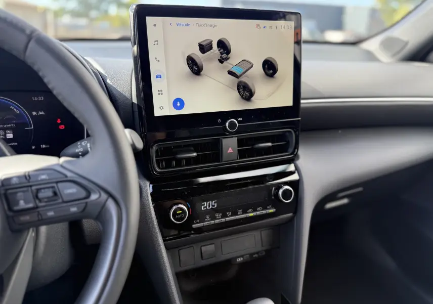 Vue intérieure de la Toyota Yaris Cross 2026, écran tactile central affichant le flux d'énergie, ambiance noire moderne.