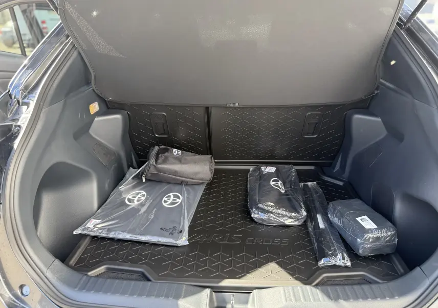 Coffre ouvert vu de l'arrière d'une Toyota Yaris Cross gris atlas, avec tapis de coffre et accessoires Toyota visibles.