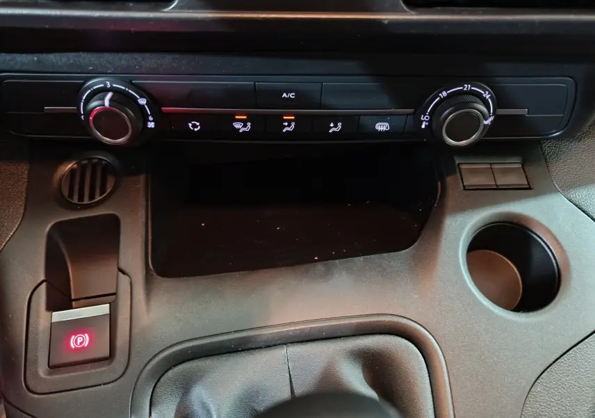 Vue rapprochée de la console centrale noire du Citroën Berlingo 2021, avec commandes climatisation et frein à main électrique allumé.