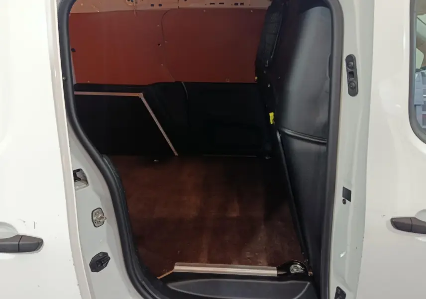Vue intérieure côté droit du coffre vide d’un utilitaire Citroën Berlingo blanc avec cloison pleine noire.