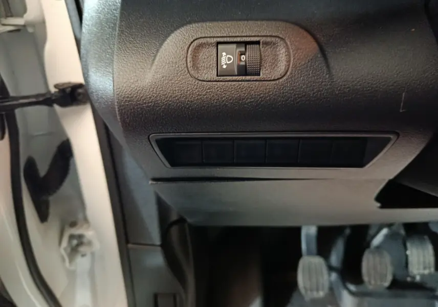Détail intérieur côté gauche du tableau de bord du Citroën Berlingo blanc, avec commande réglage hauteur phares.
