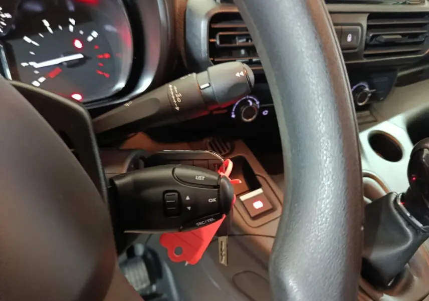 Gros plan sur le volant noir et la commande multifonction du tableau de bord intérieur du Citroën Berlingo blanc.