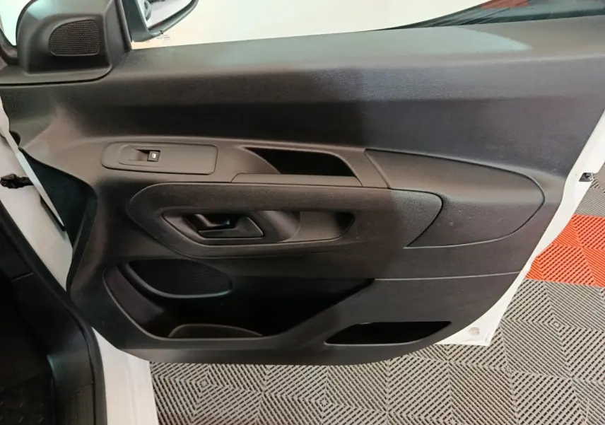Vue rapprochée de la porte avant gauche noire du Citroën Berlingo blanc, avec poignée et commande de vitre électrique.