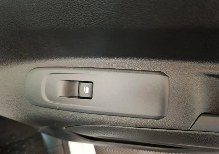 Gros plan sur le bouton de commande de vitre électrique côté conducteur dans l'intérieur noir du Citroën Berlingo blanc.