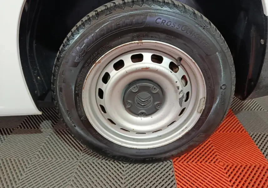 Gros plan sur la roue avant droite blanche d’un Citroën Berlingo 2021 avec jante acier et pneu Michelin CrossClimate.
