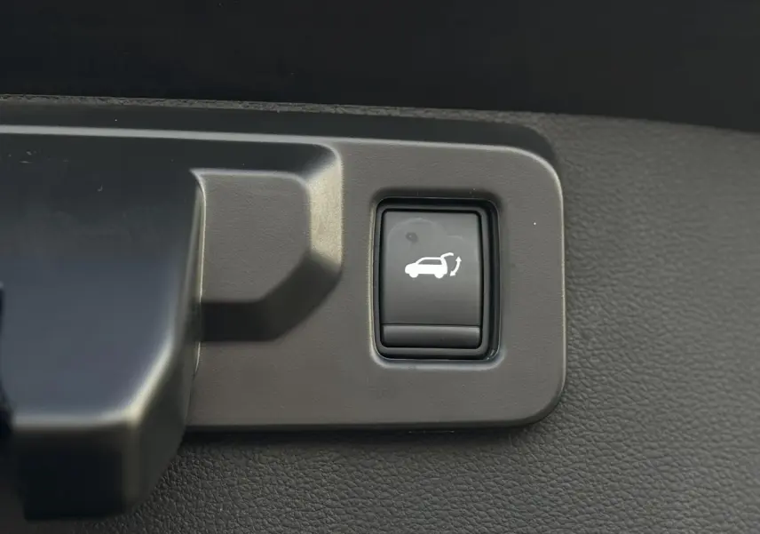 Gros plan sur le bouton d'ouverture du hayon mains libres dans l'habitacle du Renault Symbioz noir étoilé.