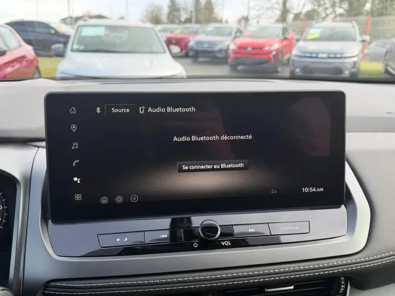 Vue intérieure centrée sur l'écran tactile du tableau de bord du Nissan Qashqai Hybrid e-POWER 2025, avec commandes audio visibles.