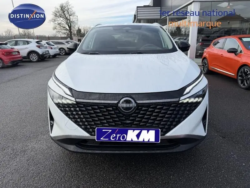 Vue avant d'un Nissan Qashqai Hybrid e-POWER 2025 en blanc nacré avec calandre noire texturée et phares LED fins.