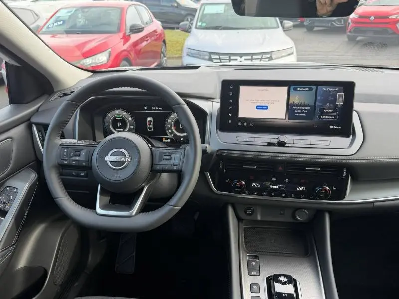 Vue intérieure du tableau de bord du Nissan Qashqai Hybrid e-POWER 2025, avec volant multifonction et écran tactile central.